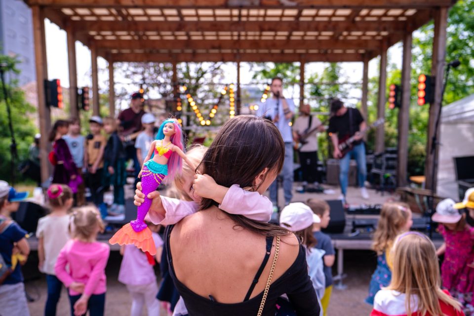 Ľudia na koncerte na Suťokruhu - matka s dieťaťom a hračkou 